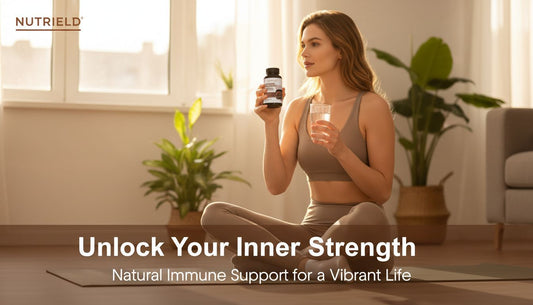 Woman in activewear holding supplement bottle and glass of water sitting on yoga mat in bright room