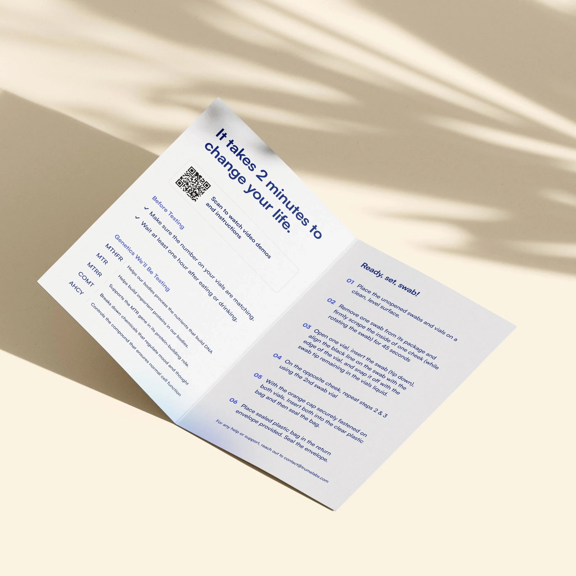 Genetic test instructions booklet with swab steps, QR code, and wellness info on soft-lit surface